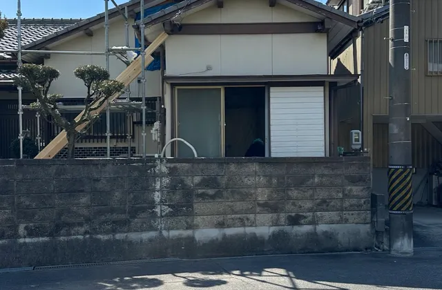 足場を組み、ブルーシートで養生しながら工事を進めている外観