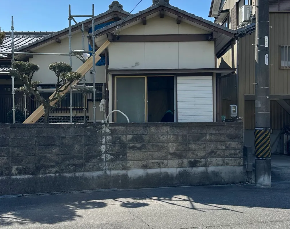 足場を組み、ブルーシートで養生しながら工事を進めている外観